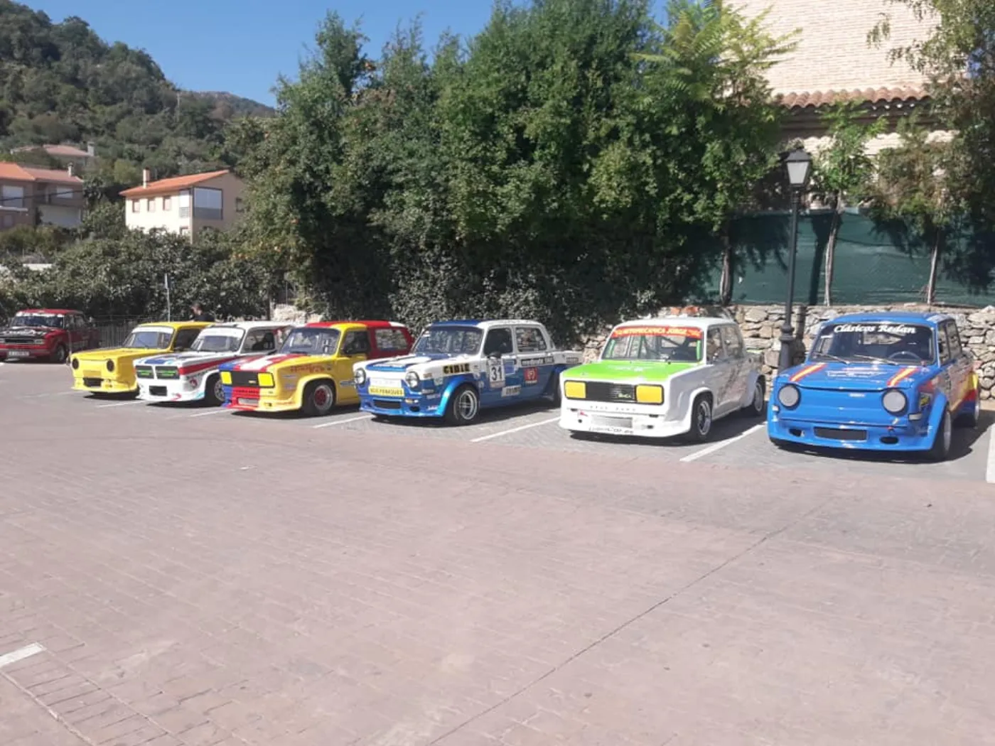 Fila de coches clásicos de competición aparcados en el parque cerrado